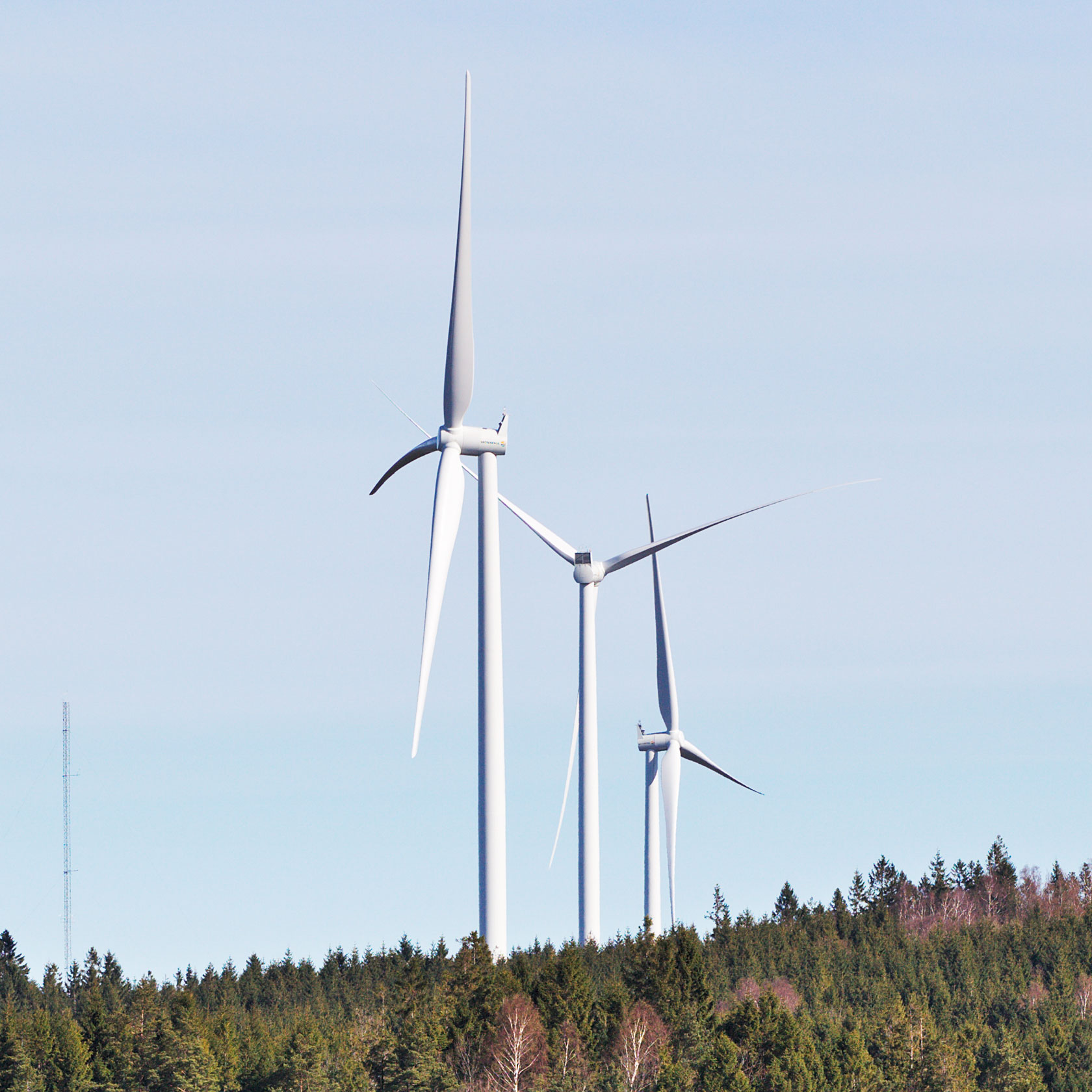 Tre vindkraftverk på en skogshöjd