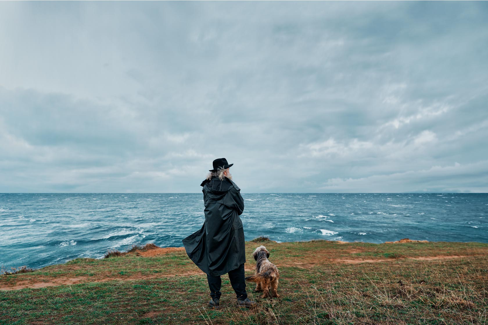 A man and his dog looking out over the sea