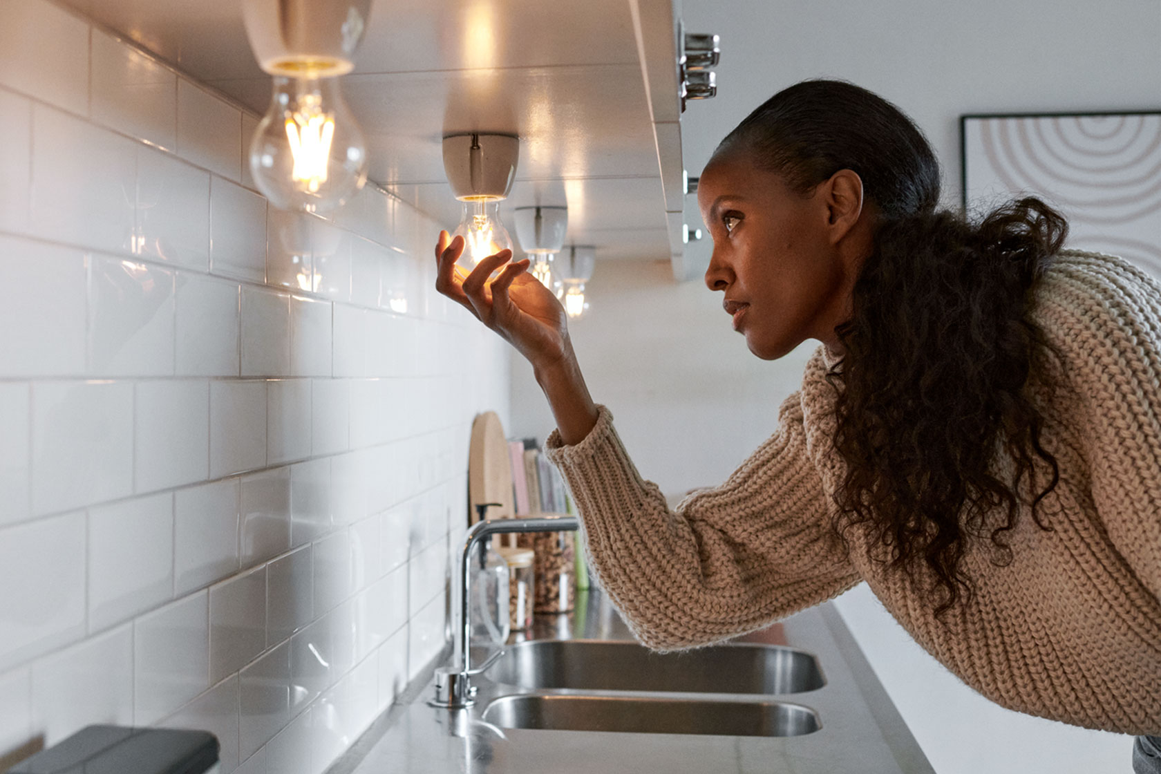 Woman changing a lightbulb in a kitchen