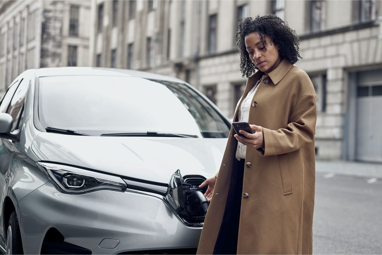 A woman in a city charging her electric car