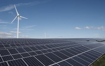 Image of solar panels in front of a wind turbine.