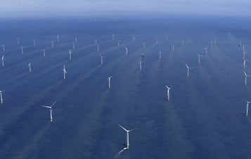 Image of rows of wind turbines located in the blue ocean.