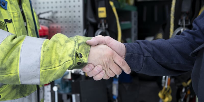 Handshake between two people in workwear.