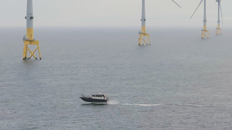 An image of a CTV travelling across the sea with wind turbines in the background An image of a CTV travelling across the sea with wind turbines in the background