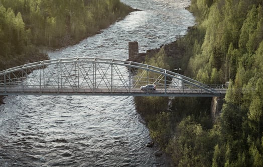 Car crossing a steel bridge over a river surrounded by forest. Car crossing a steel bridge over a river surrounded by forest.