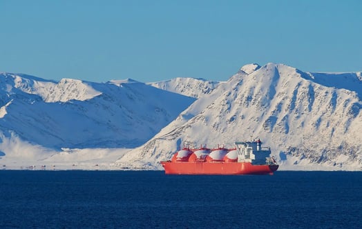 A large bright‑orange liquefied natural gas (LNG) tanker floats on deep blue water in front of a backdrop of tall, snow‑covered mountains under a clear blue sky. A large bright‑orange liquefied natural gas (LNG) tanker floats on deep blue water in front of a backdrop of tall, snow‑covered mountains under a clear blue sky.