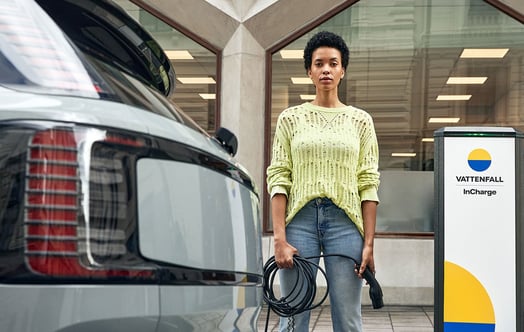 Woman standing next to an electric car and a Vattenfall InCharge charging post Woman standing next to an electric car and a Vattenfall InCharge charging post