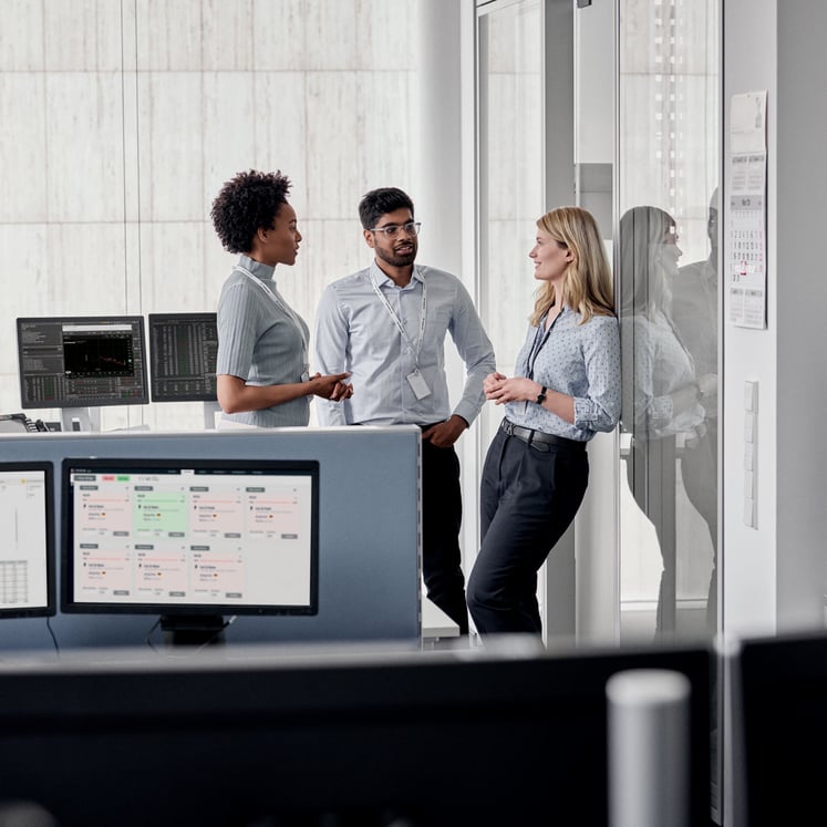 Three colleagues in conversation on the trading floor Three colleagues in conversation on the trading floor