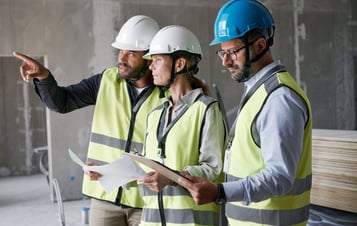 Drei Personen in Schutzkleidung auf Baustelle Drei Personen in Schutzkleidung auf Baustelle