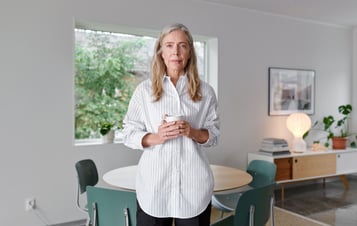Frau eine Tasse haltend in die Kamera schauend Frau eine Tasse haltend in die Kamera schauend
