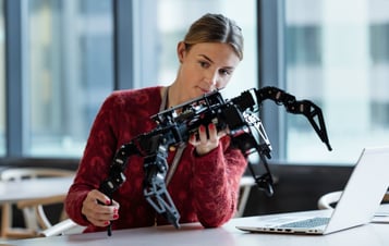 Mitarbeiterin betrachtet eine Robotereinheit Mitarbeiterin betrachtet eine Robotereinheit