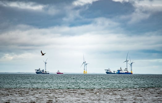 Offshore wind turbines at sea with installation vessels in the background. Offshore wind turbines at sea with installation vessels in the background.