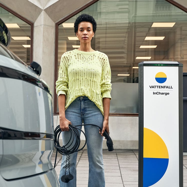 Eine Frau, die ein Ladekabel für ein Elektroauto in der Hand hält Eine Frau, die ein Ladekabel für ein Elektroauto in der Hand hält