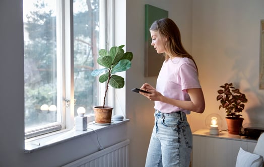 Femme près d'une fenêtre allumant une lampe Femme près d'une fenêtre allumant une lampe