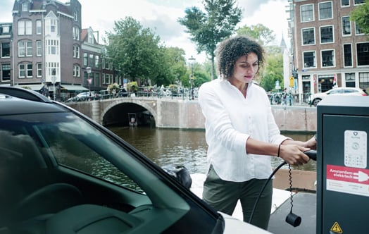 Vrouw laadt auto op aan een Amsterdamse gracht_Vattenfall Vrouw laadt auto op aan een Amsterdamse gracht_Vattenfall