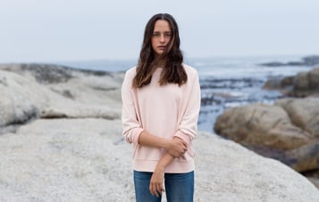 En flicka i rosa tröja på klippor vid havet En flicka i rosa tröja på klippor vid havet