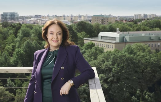 Anna Borg, Vattenfalls vd, står lutad mot ett räcke på en balkong, med hus och grönskande träd i bakgrunden. Anna Borg, Vattenfalls vd, står lutad mot ett räcke på en balkong, med hus och grönskande träd i bakgrunden.