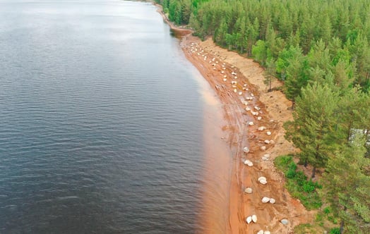 Flygbild över älv där stenblock placerats längs strandlinjen. Flygbild över älv där stenblock placerats längs strandlinjen.