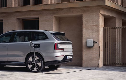 Volvo EX90 på laddning utanför en tegelbyggnad. Volvo EX90 på laddning utanför en tegelbyggnad.