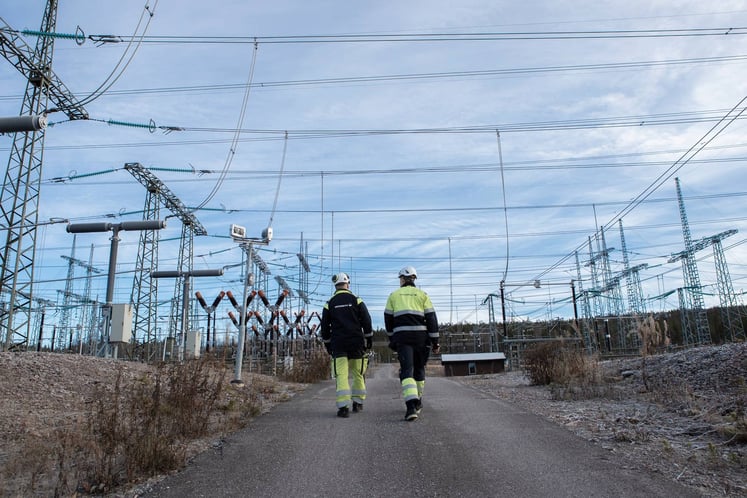 Två Vattenfall-medarbetare som går under kraftledningar i Harsprånget Två Vattenfall-medarbetare som går under kraftledningar i Harsprånget