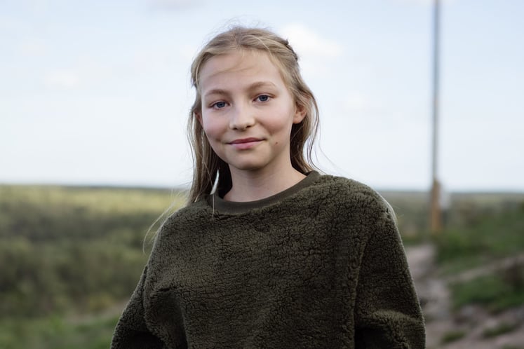 Flicka med grön tröja tittar in i kameran Flicka med grön tröja tittar in i kameran